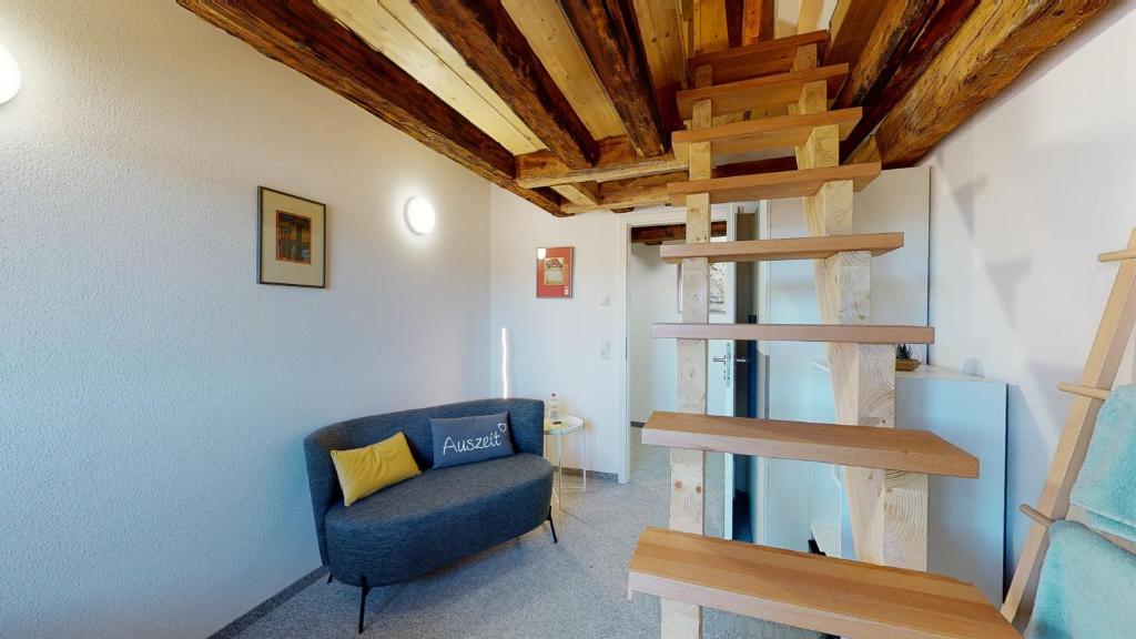a living room with a blue chair and a spiral staircase at Karl V - Geschichte leben im Herzen der Altstadt in Schwäbisch Hall