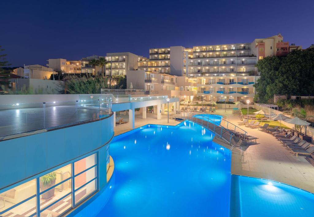 a resort with a swimming pool at night at Iolida Beach by Smile Hotels in Agia Marina Nea Kydonias