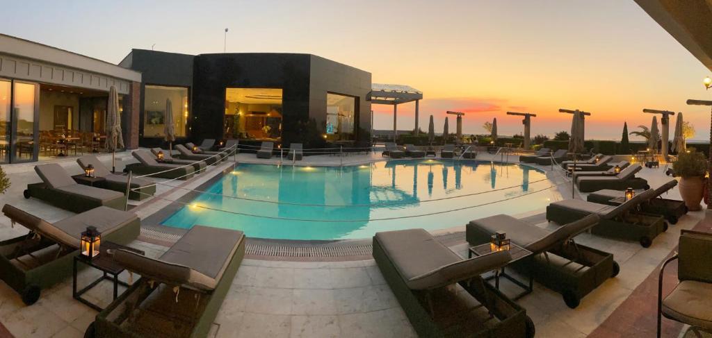 a large swimming pool with chairs and a building at Royal Hotel Thessaloniki in Perea