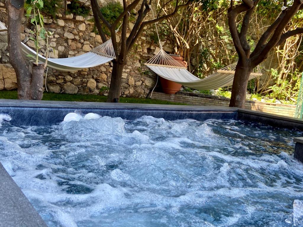a hot tub with hammocks in a yard with trees at Relais 147 - Luxury b&b in Taormina