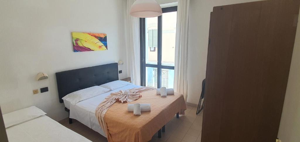Hotel Vela Azzurra في ريميني: غرفة نوم بسرير وطاولة عليها شماعات