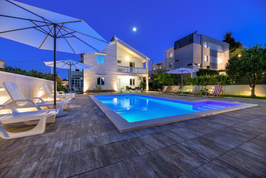 a villa with a swimming pool at night at Pool house LUKA in Zadar