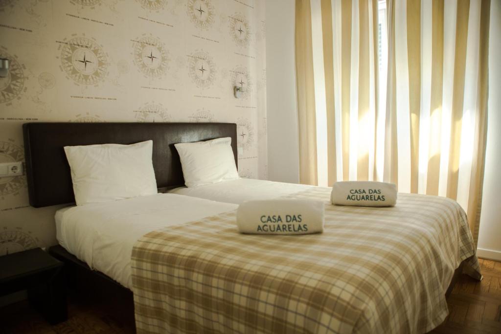 a bedroom with a bed with two pillows on it at Casa das Aguarelas - Apartamentos in Ericeira