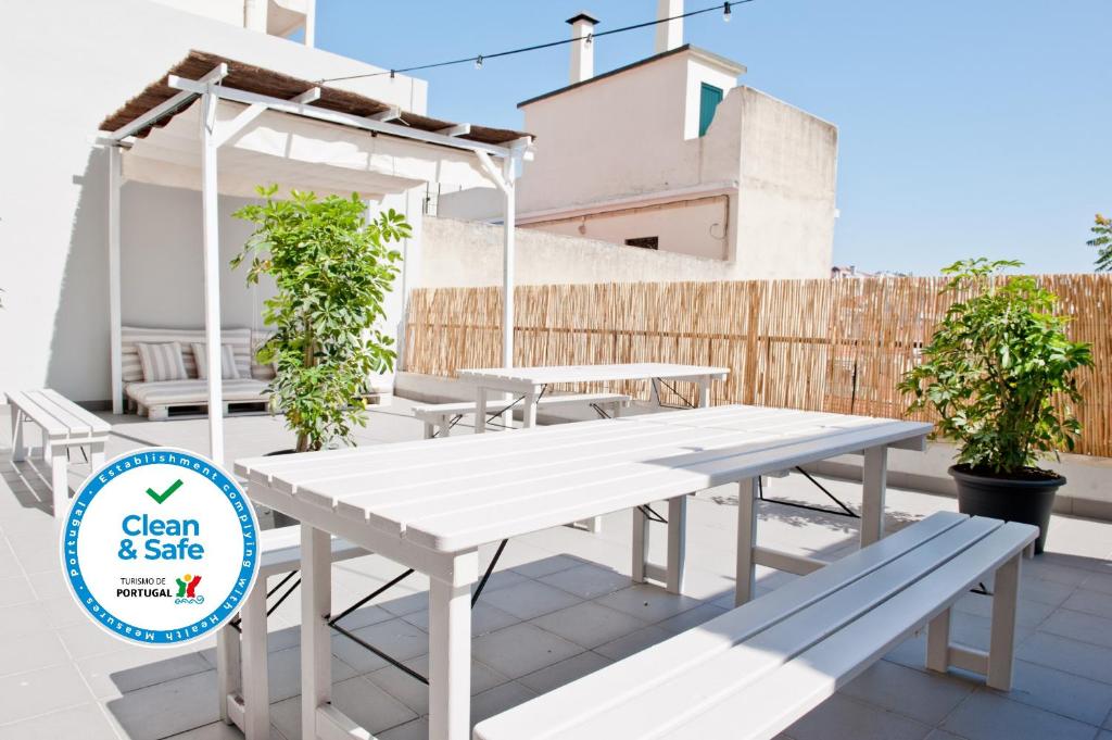 - une table de pique-nique blanche et des bancs sur une terrasse dans l'établissement Red, Red Wine Apartment 3B, à Lisbonne