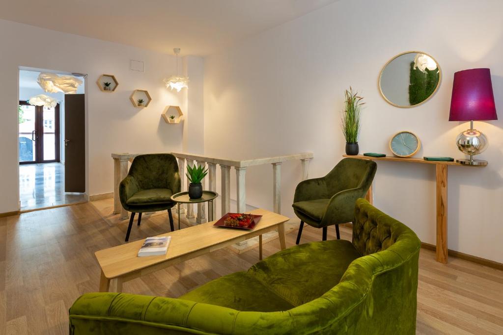 sala de estar con sofá verde y 2 sillas en Lagom Hotel en Bucarest