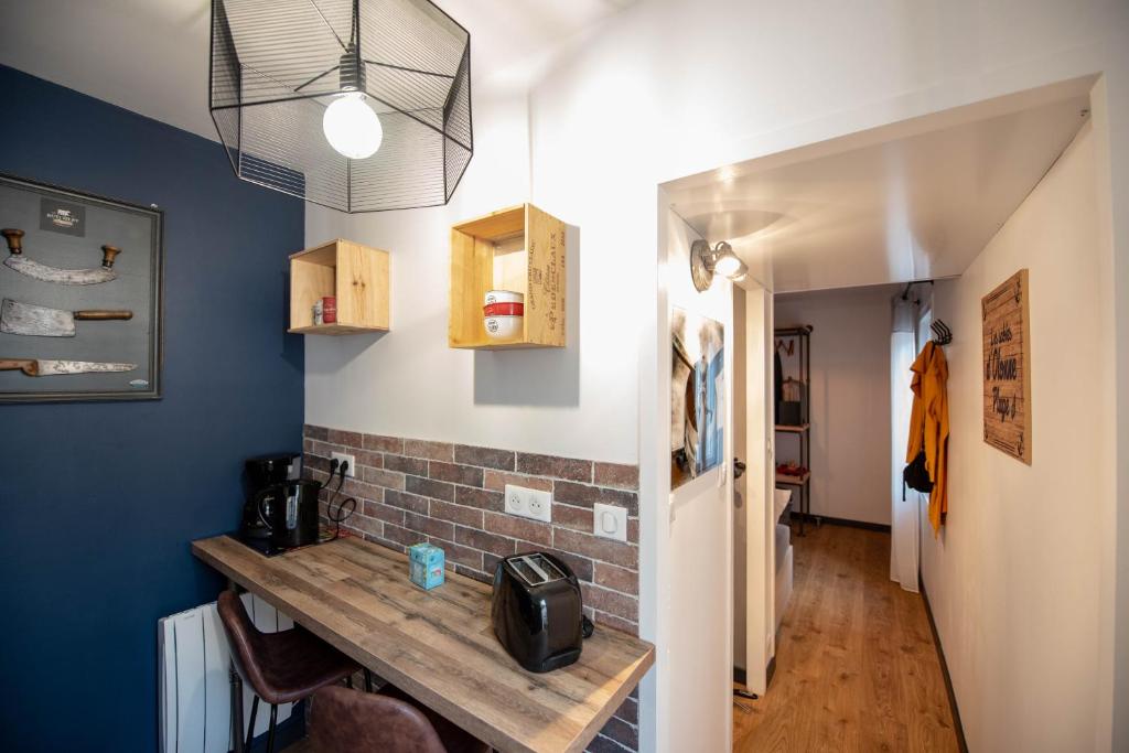 レ・サ​​ーブル・ドロンヌにあるMa Location Sablaise - Appart' Aragoの青い壁の客室で、木製テーブルが備わります。