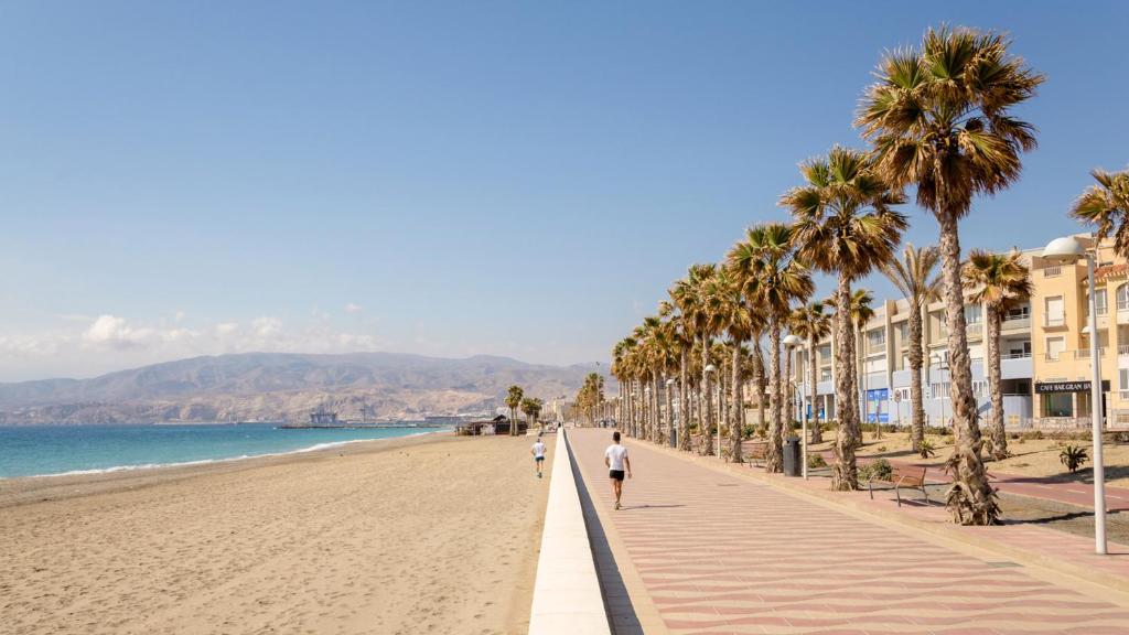 een strand met palmbomen en mensen die erop lopen bij Apartamento San Juan Bosco in Almería