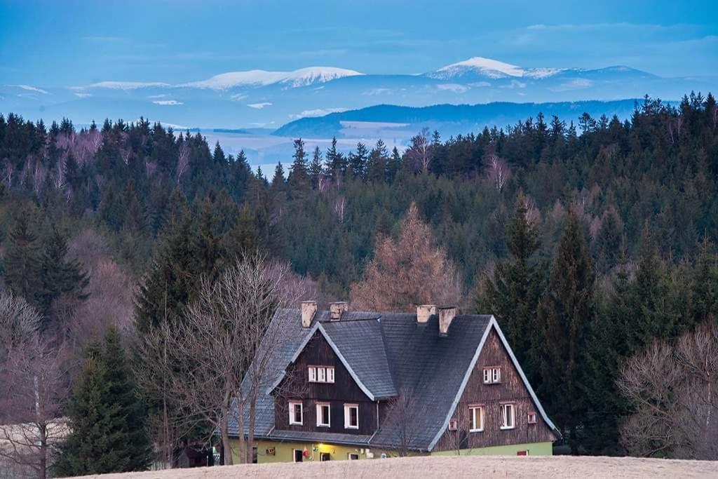 una casa en una colina con montañas en el fondo en Schronisko PTTK Pasterka, en Pasterka