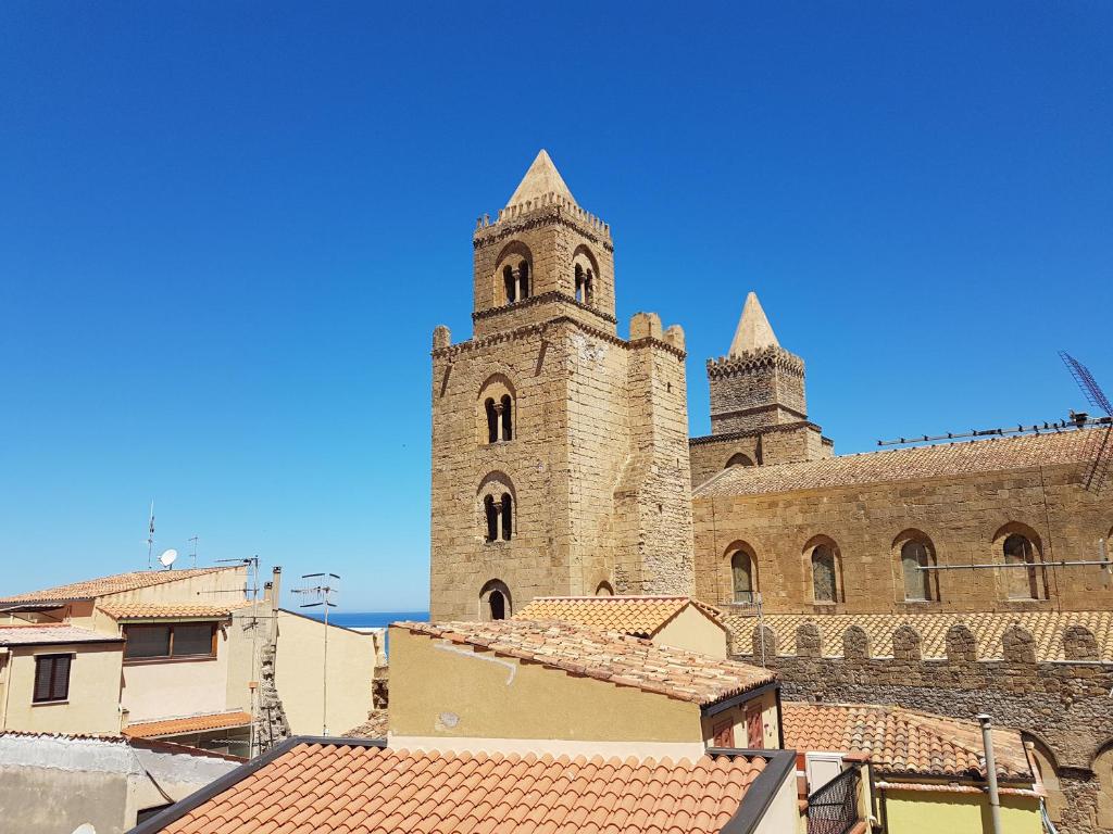 a large stone building with two towers and roofs at Duomo Rooms Cefalù in Cefalù