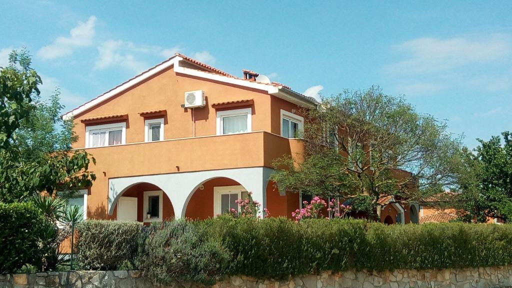a large orange house with bushes in front of it at Apartman Perci Vrh in Tar