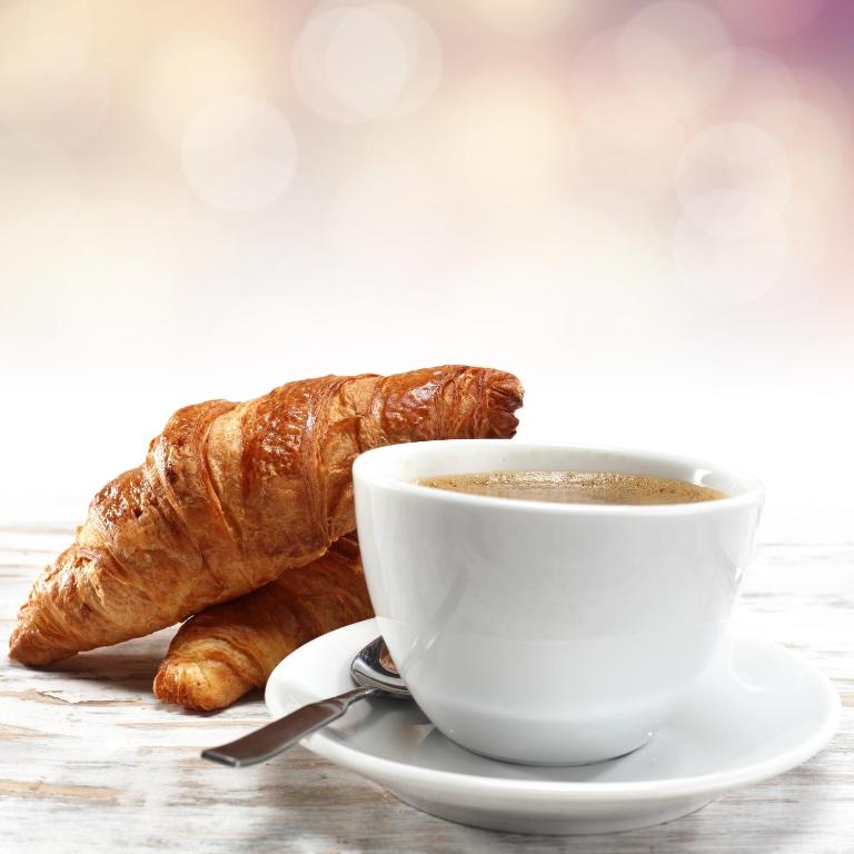 a cup of coffee and a croissant on a table at Leonardo Hotel Aberdeen in Aberdeen