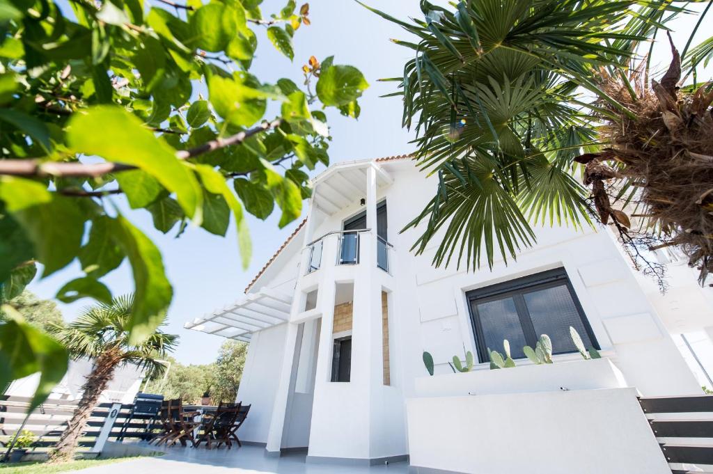 une maison blanche avec des palmiers au premier plan dans l'établissement Villa Sunset Albatross, à Potidée