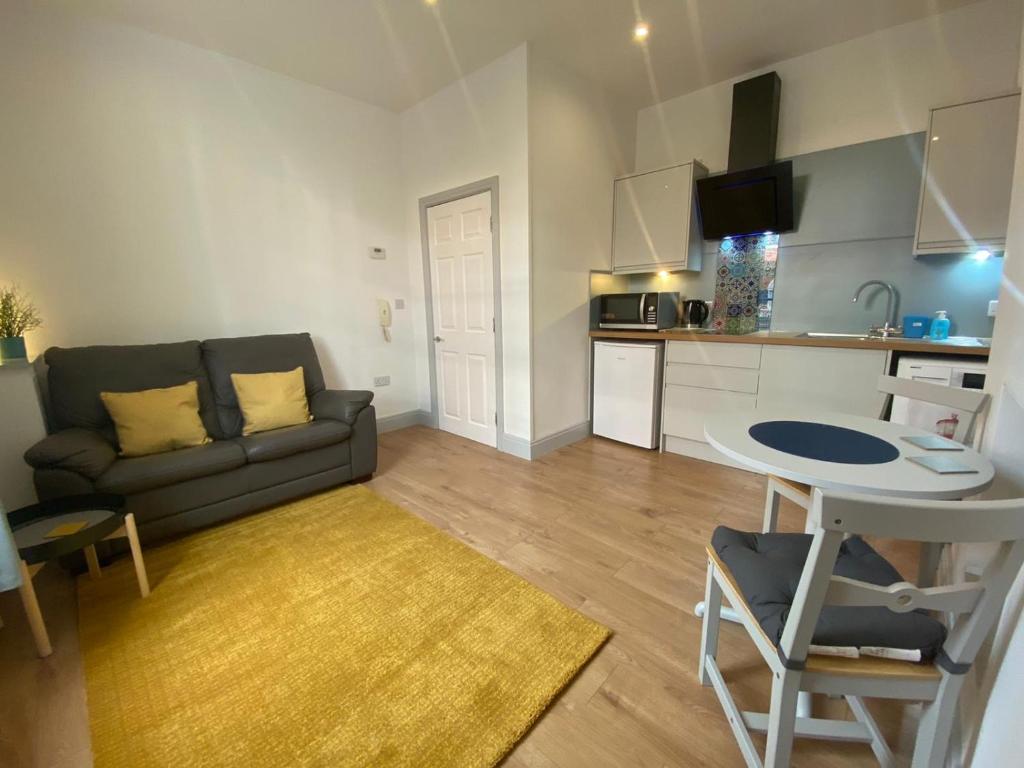 a living room with a couch and a table and a kitchen at Avenham Apartments in Preston