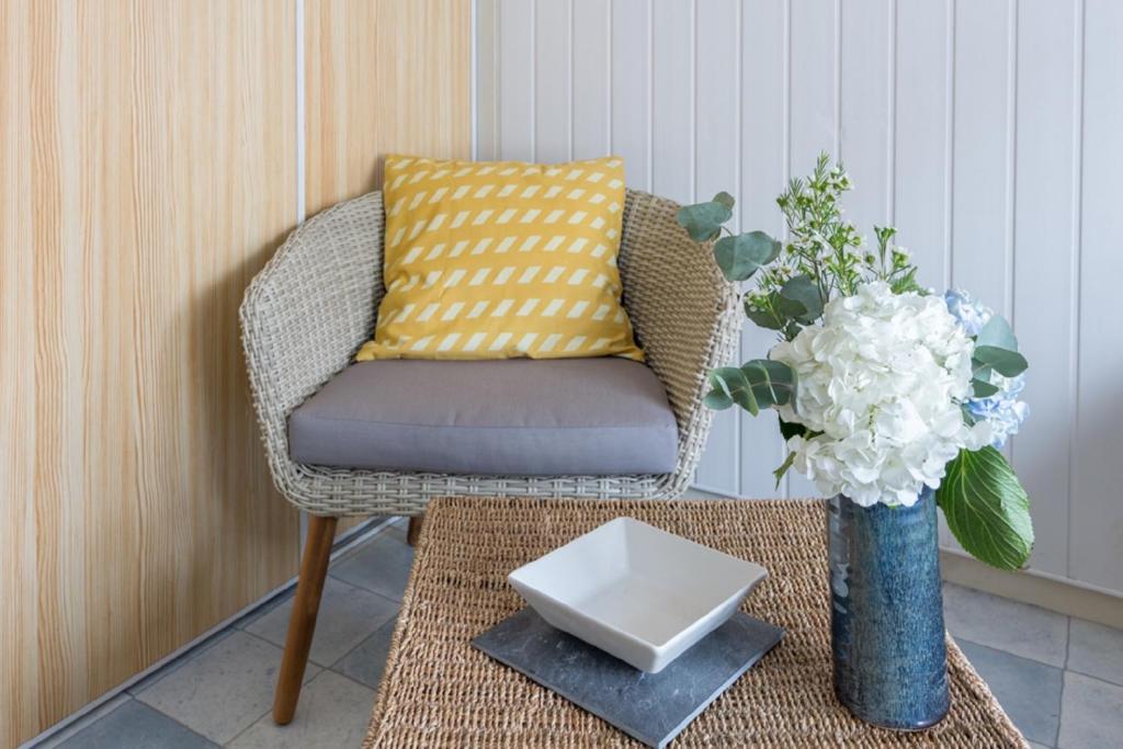 une chaise et une table avec un vase de fleurs dans l'établissement ile de Nole, à Rochefort