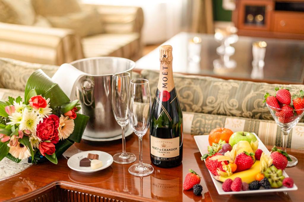 a bottle of wine and glasses on a table with fruit at Spa Hotel Imperial in Karlovy Vary