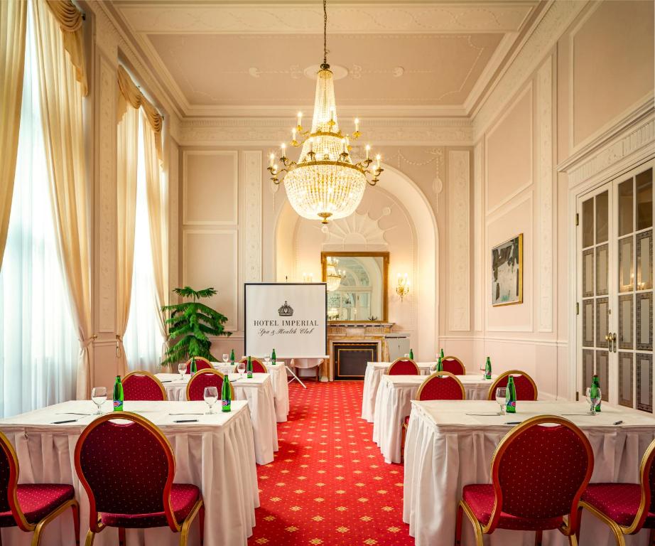 a conference room with tables and chairs and a screen at Spa Hotel Imperial in Karlovy Vary