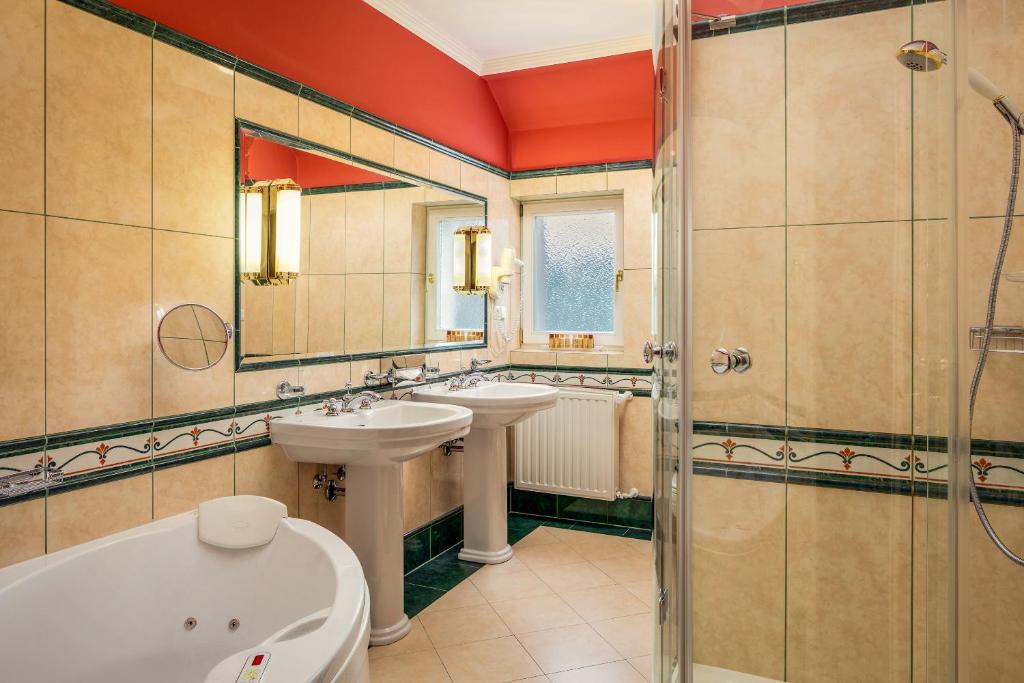 a bathroom with two sinks and a tub and a shower at Spa Hotel Imperial in Karlovy Vary