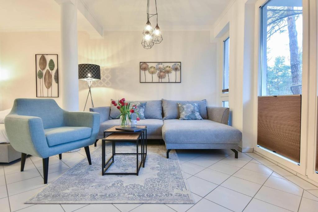 sala de estar con sofá azul y 2 sillas en Villa Marfa Wohnung 5 en Heringsdorf