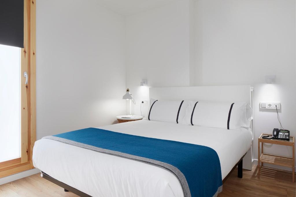 a bedroom with a large white bed with a blue blanket at Hotel SANSEbay in Donostia-San Sebastián