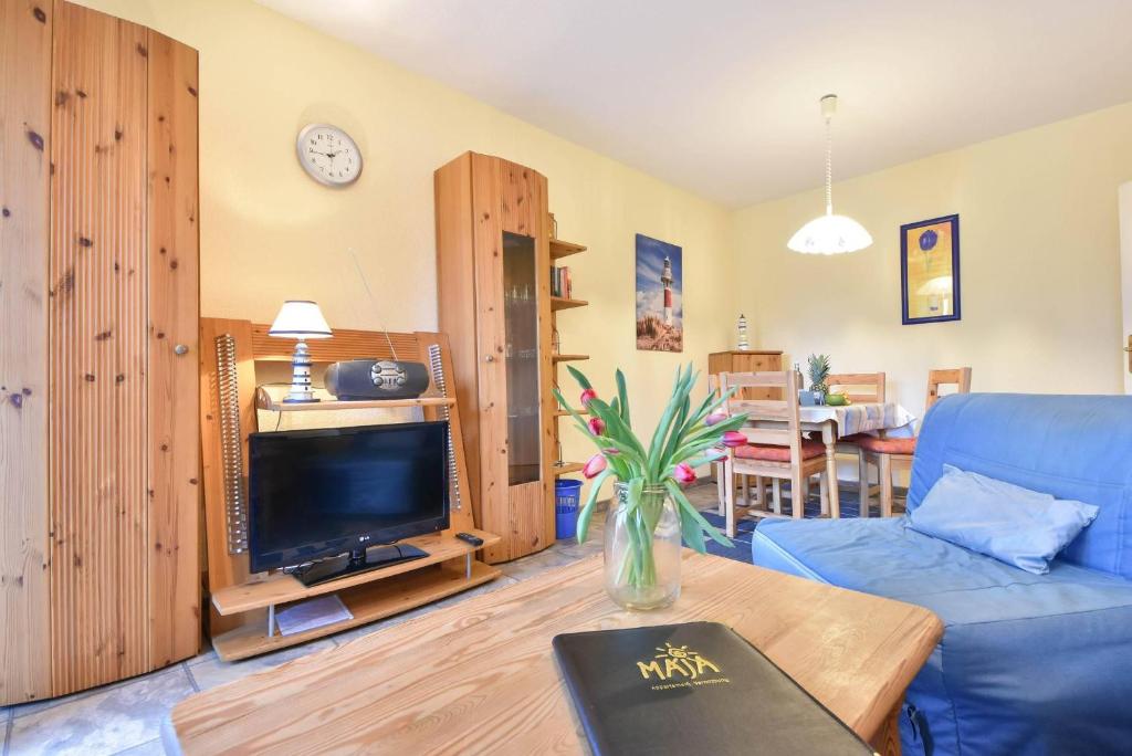 uma sala de estar com um sofá azul e uma televisão em Haus Dünenweg 01 em Heringsdorf