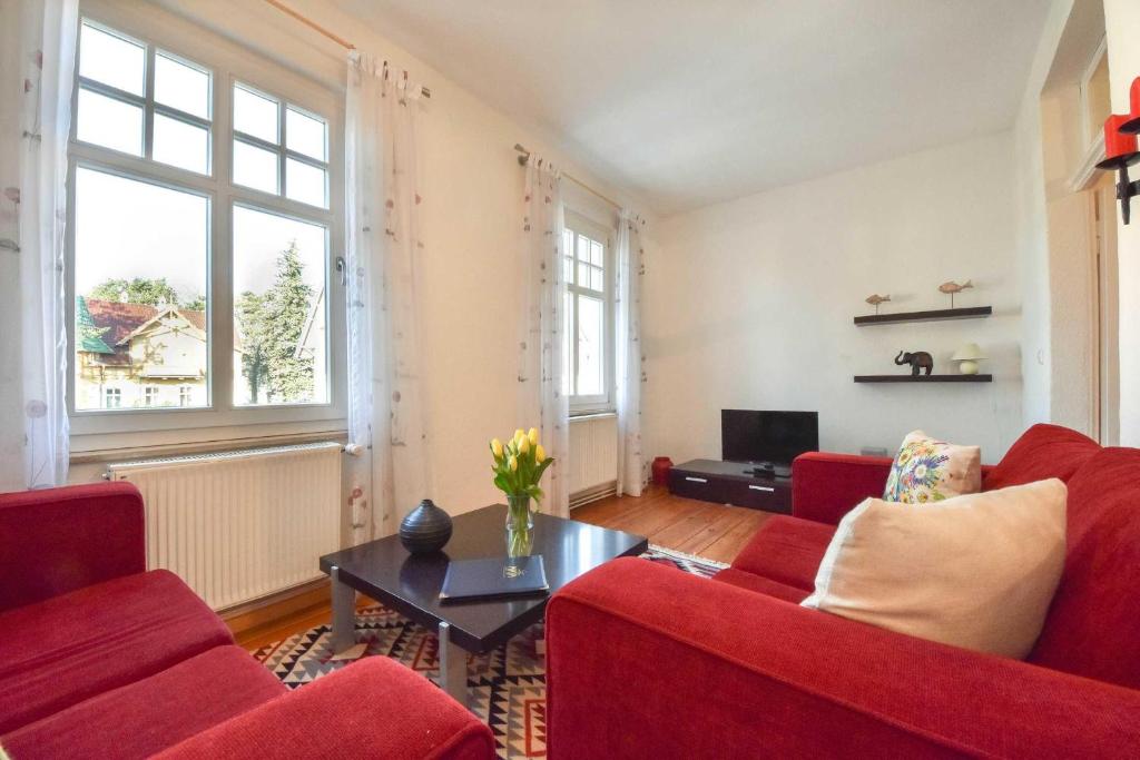 una sala de estar con sofás rojos y una mesa. en Villa Emmy Wohnung 8, en Heringsdorf
