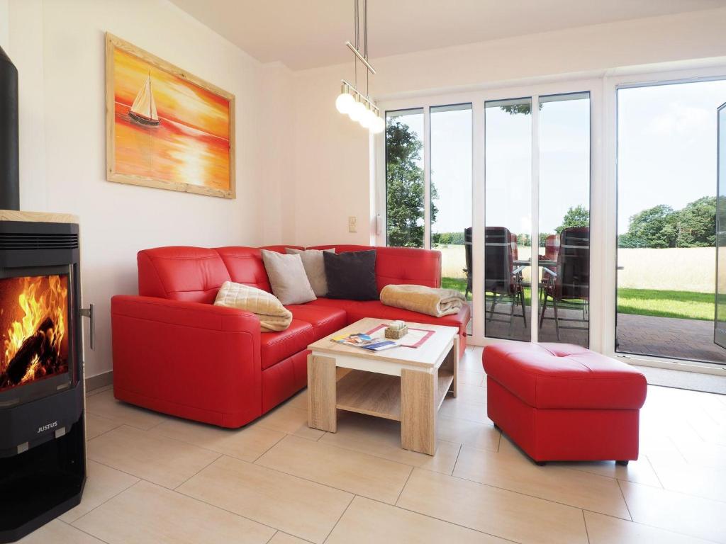 sala de estar con sofá rojo y chimenea en Ferienhaus Birgit, en Korswandt
