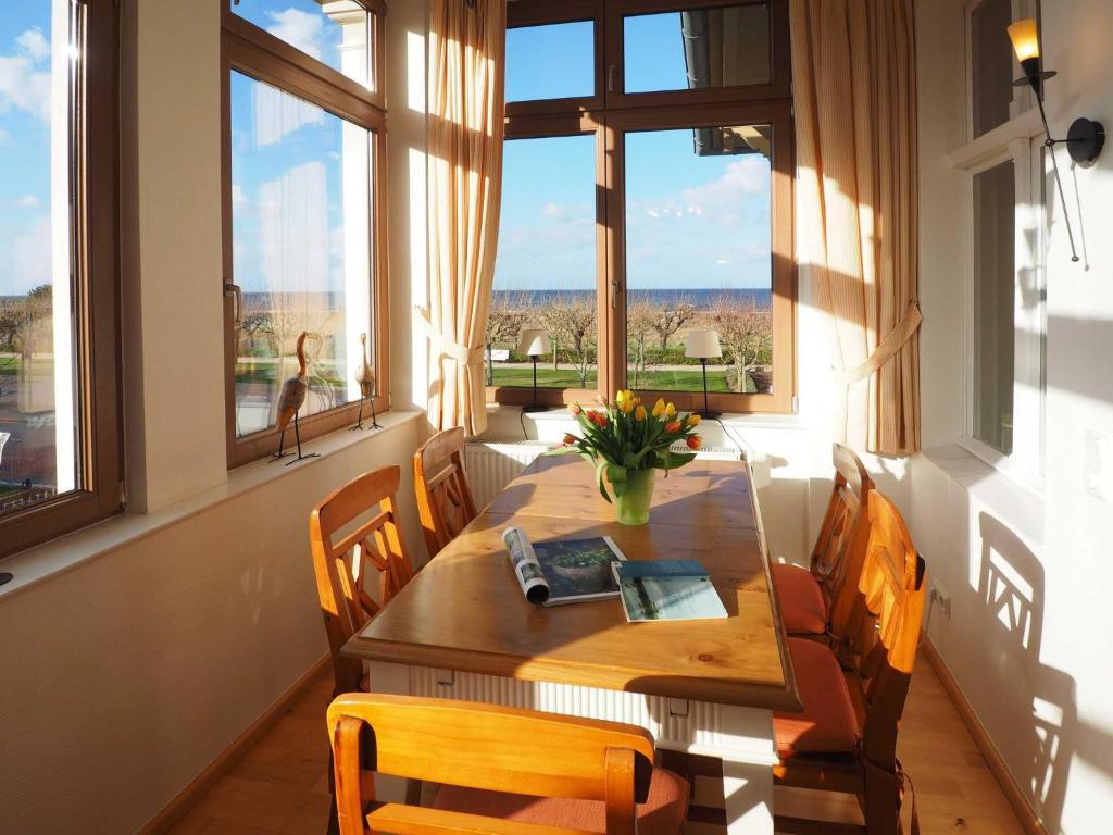 comedor con mesa, sillas y ventanas en Haus Meerblick Wohnung 7, en Ahlbeck