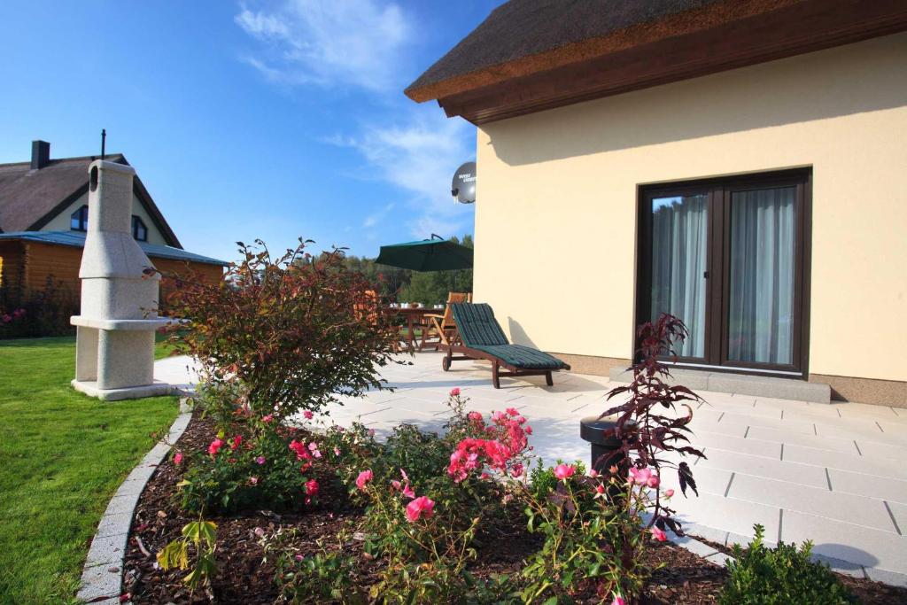 a patio with a bench and flowers next to a house at Ferienhaus Seestrand - mit Sauna in Kolpinsee