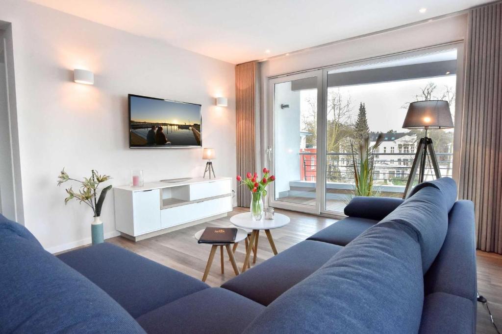 uma sala de estar com um sofá azul e uma grande janela em Haus Seven Seas - Wohnung Pazifik em Heringsdorf