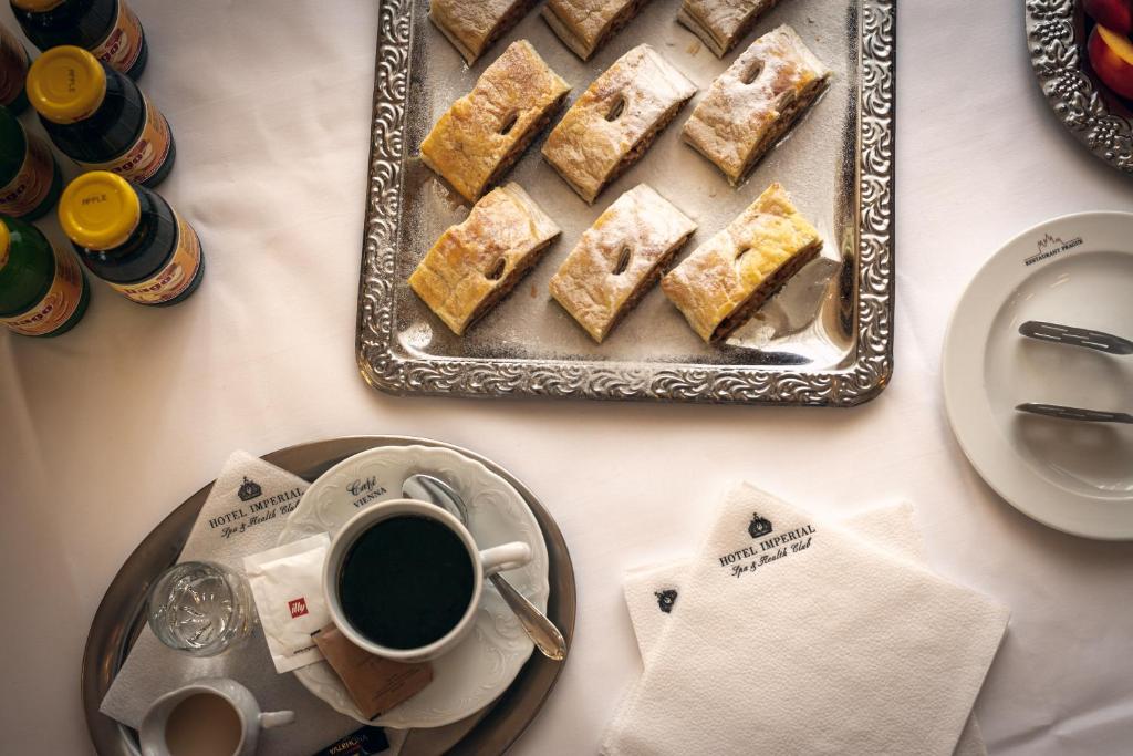 a table with a tray of cake and a cup of coffee at Spa Hotel Imperial in Karlovy Vary