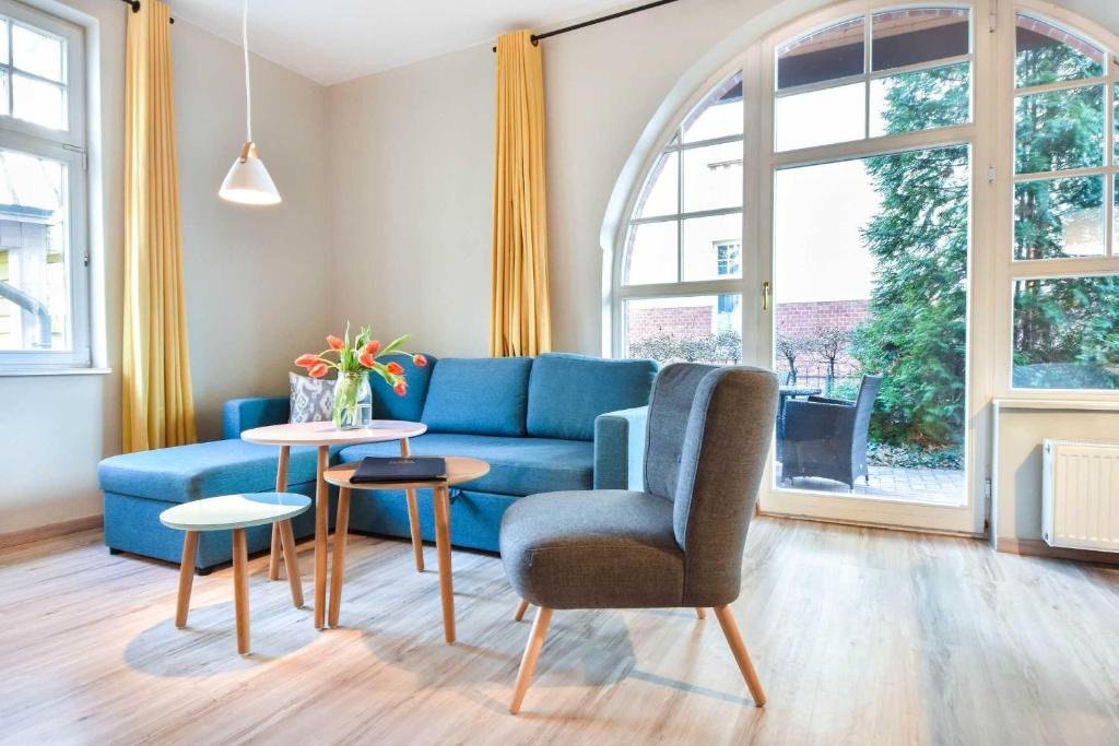 - un salon avec un canapé bleu et une table dans l'établissement Haus Kogge Wohnung 1, à Heringsdorf