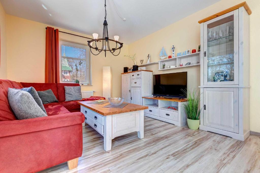 ein Wohnzimmer mit einem roten Sofa und einem Tisch in der Unterkunft Ostseepark Karavelle 37 in Heringsdorf