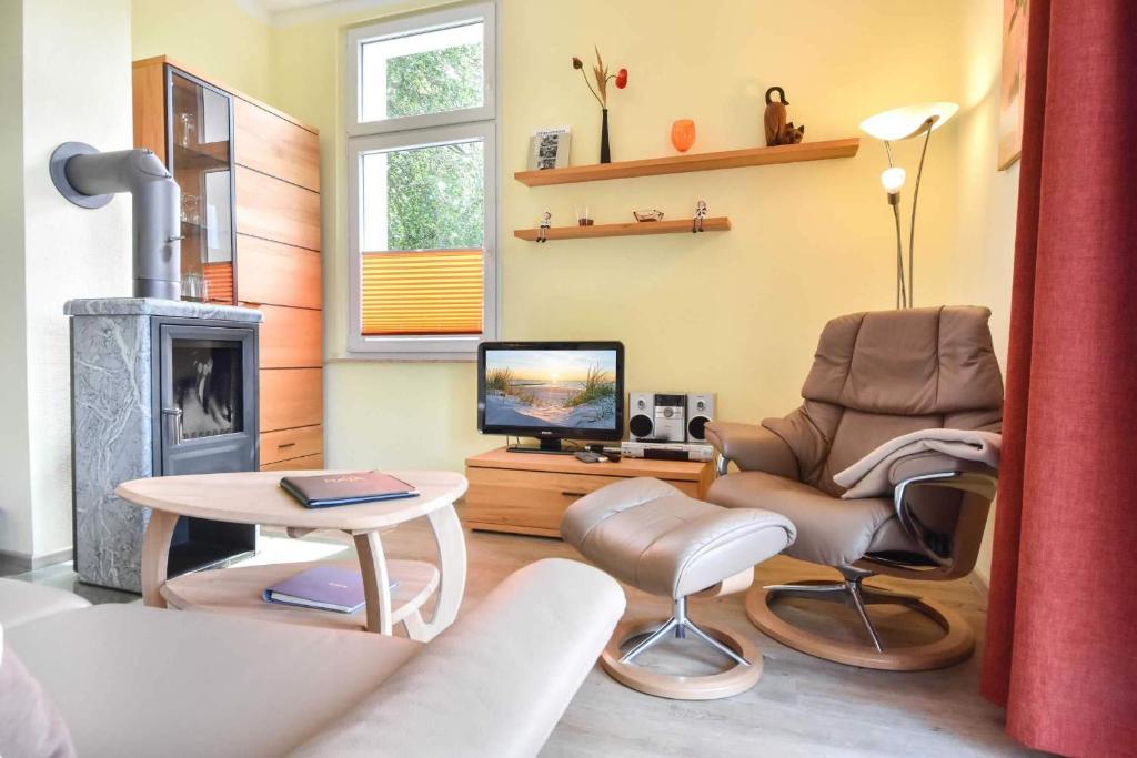 ein Wohnzimmer mit einem Kamin, einem Stuhl und einem TV in der Unterkunft (27a) Villa Seestern 05 in Heringsdorf