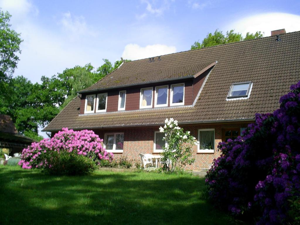 ein Haus mit rosa Blumen im Hof in der Unterkunft Rhododendronhof in Behringen
