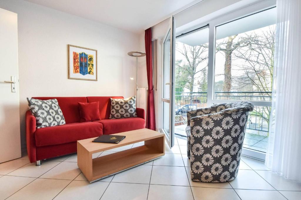 ein Wohnzimmer mit einem roten Sofa und einem Stuhl in der Unterkunft Haus an der Düne Wohnung 04 in Heringsdorf