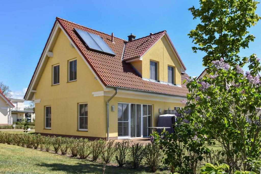 una casa amarilla con techo rojo en Ferienhaus Waldhaus en Korswandt