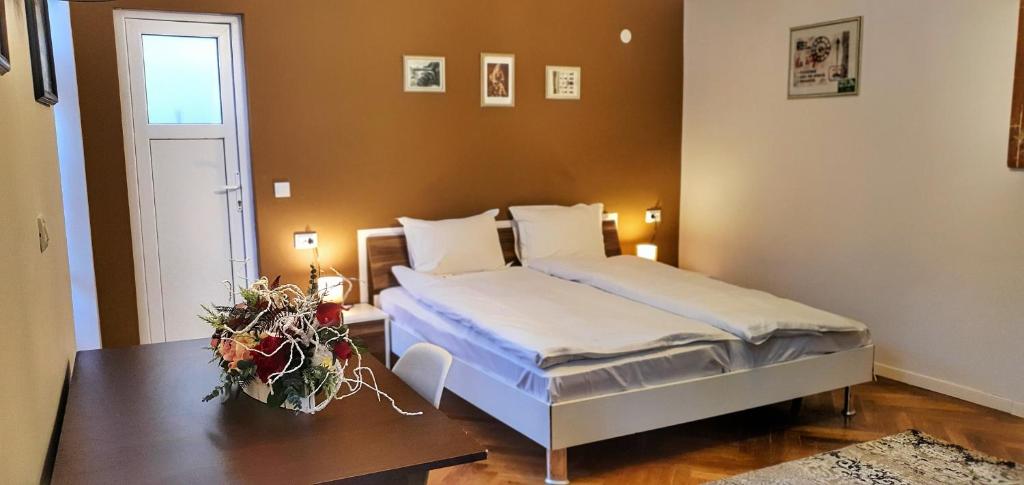 ein Schlafzimmer mit einem Bett und einem Tisch mit Blumen darauf in der Unterkunft Casa Crown in Braşov