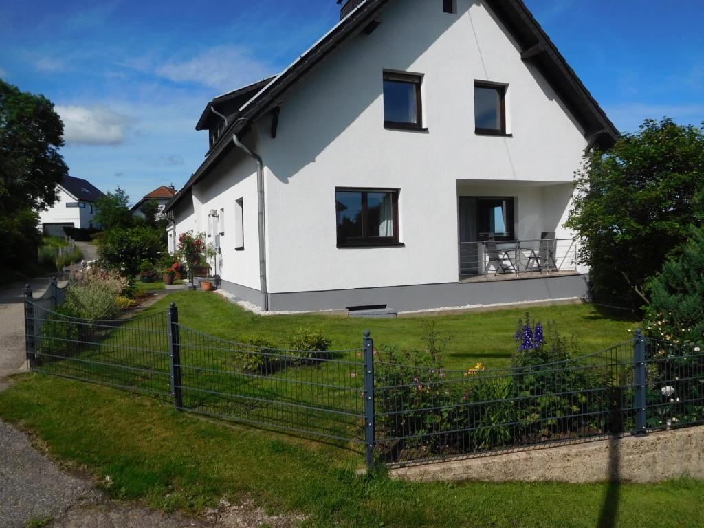 a white house with a fence at Ferienwohnung Charly in Hellenthal