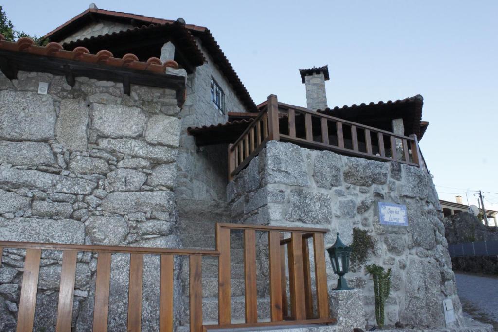 a stone building with a wooden fence next to it at Casa das Leiras in Vieira do Minho