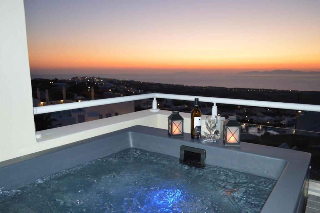 a bath tub with wine bottles and candles on a balcony at Kiklamino Sunset Studios in Oia