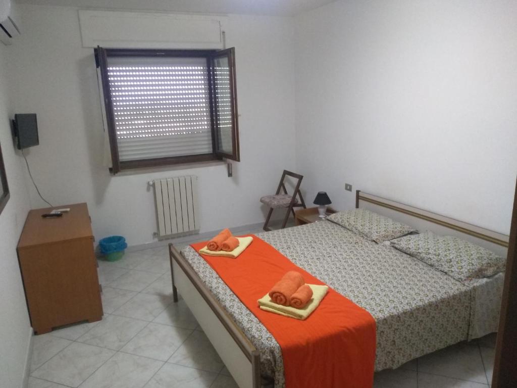 1 dormitorio con 2 camas con sábanas de color naranja y ventana en Home Sweet Home, en Matera