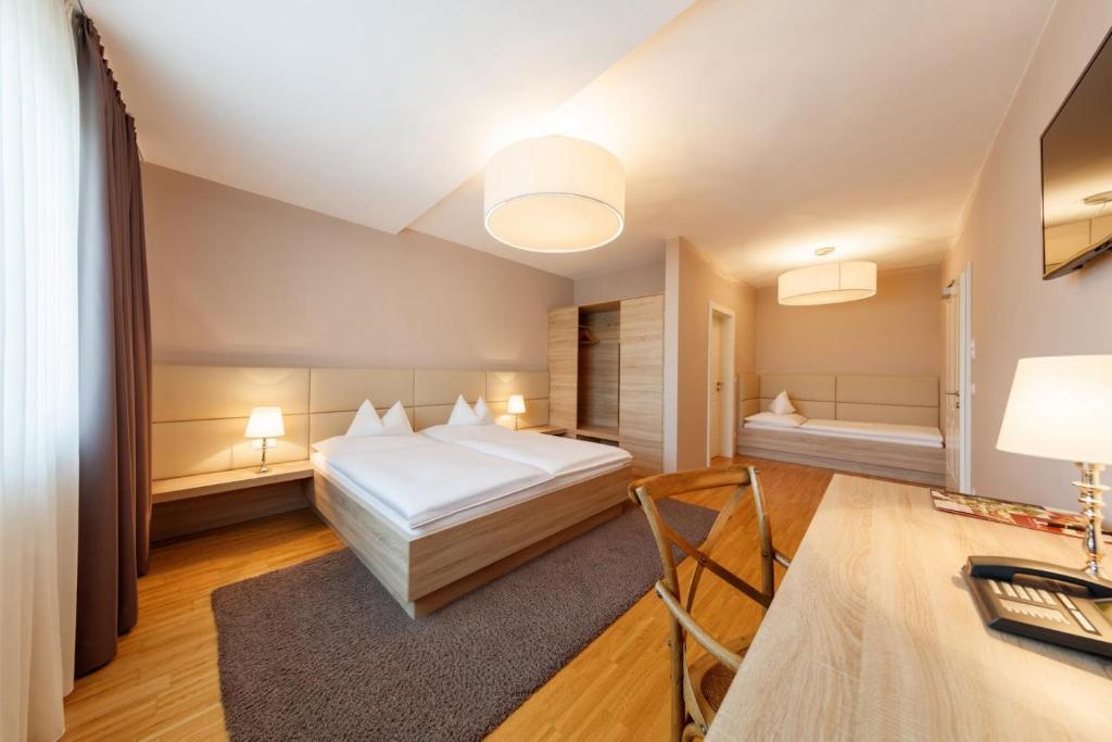 a bedroom with a bed and a desk in a room at Pfeiler's Bürgerstüberl - Hotel in Feldbach