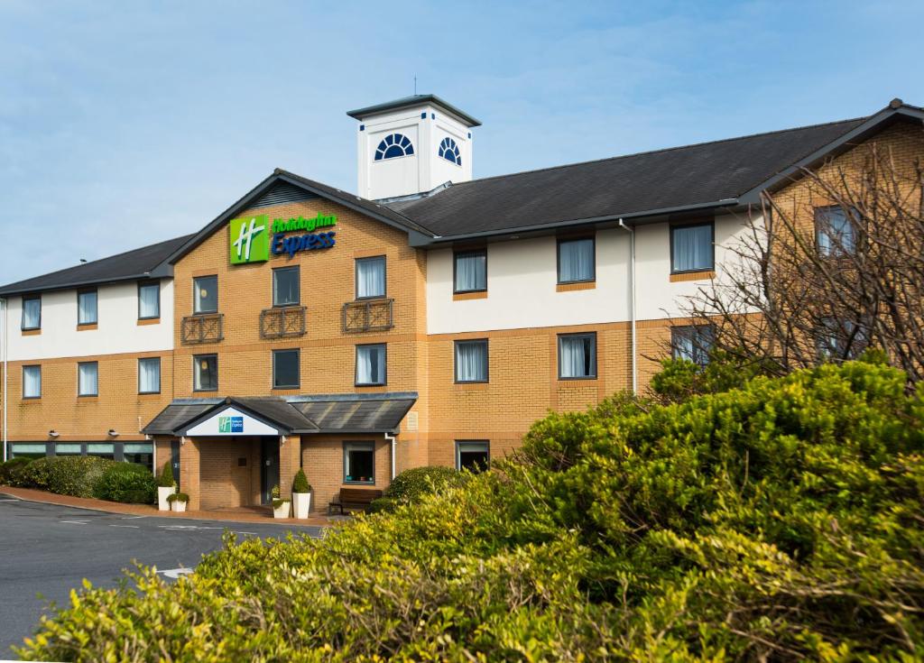 a hotel with a clock tower on top of it at Holiday Inn Express Swansea East, an IHG Hotel in Swansea