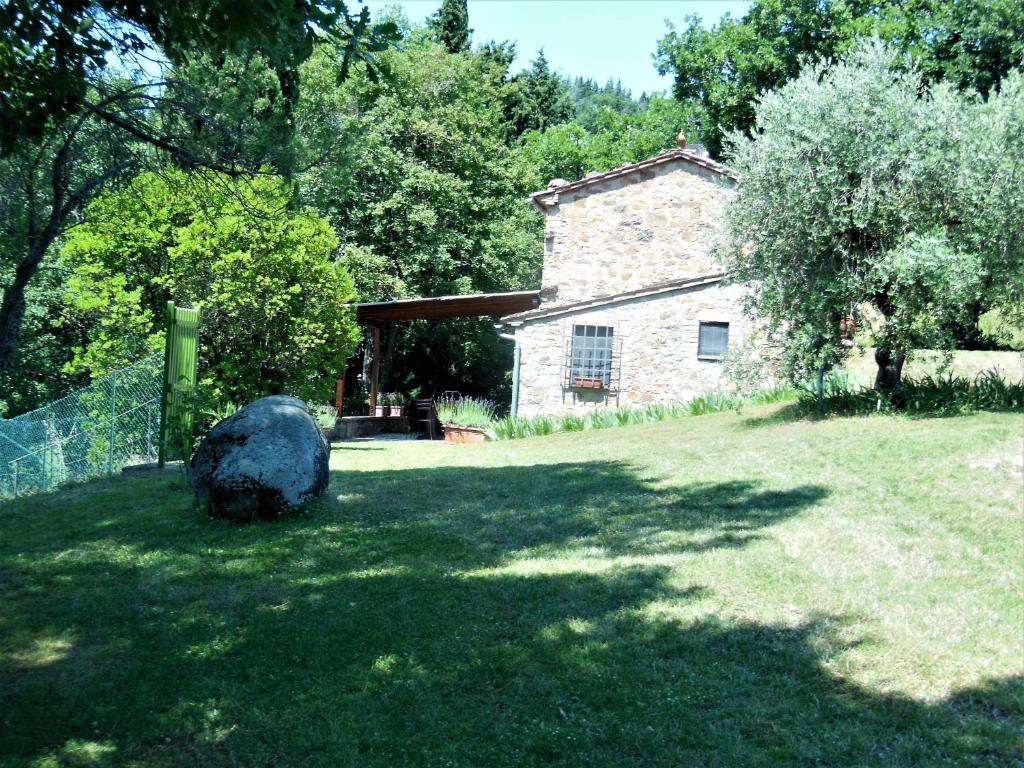 a stone house with a large rock in the yard at La Fontaiola in Le Piazze