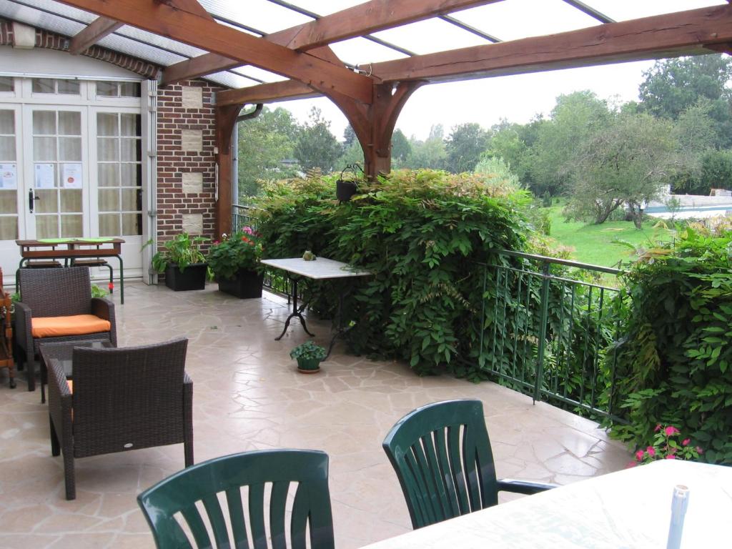 a patio with chairs and tables and a wooden pergola at Moulin de Chappes in Chappes