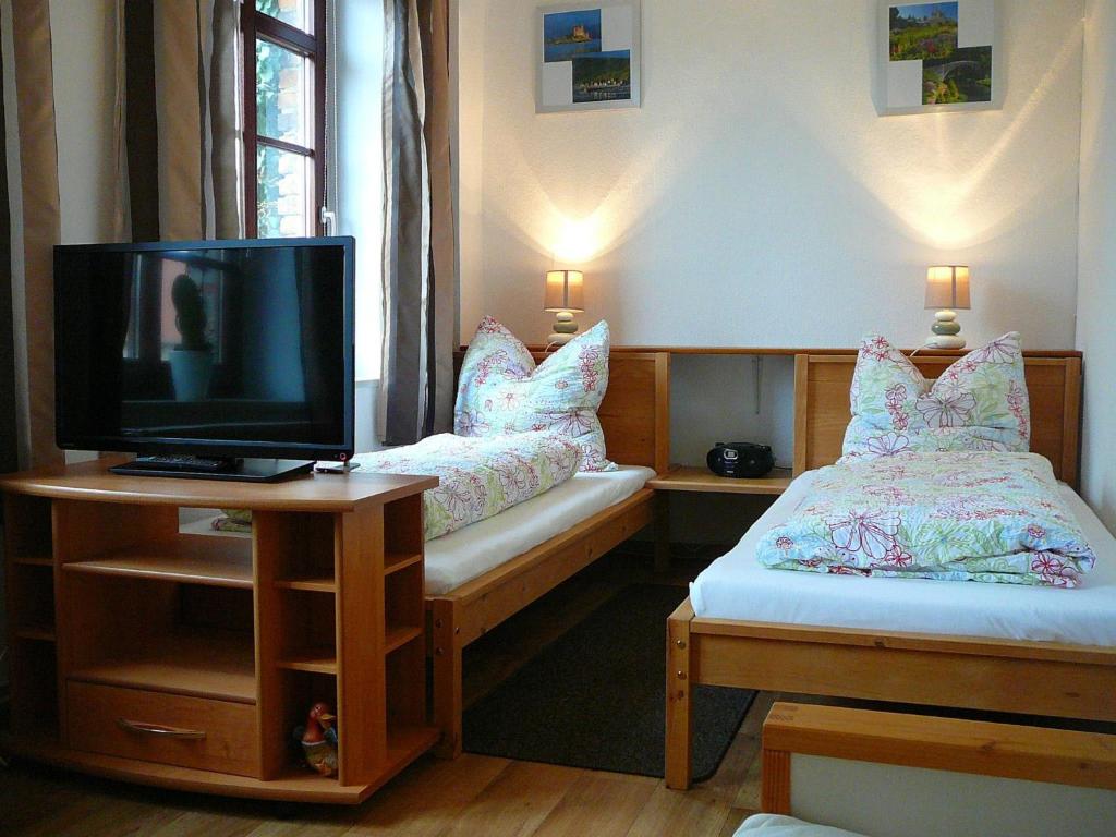 HecklingenにあるFerienwohnung Landwirtschaftliches Gut Taentzlerのベッド2台、テレビ、テーブルが備わる客室です。