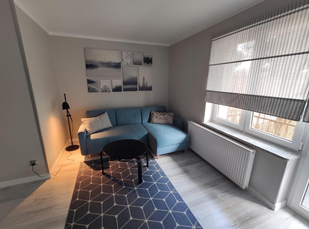 a living room with a blue couch and a table at Apartament Centrum Bartoszyce in Bartoszyce