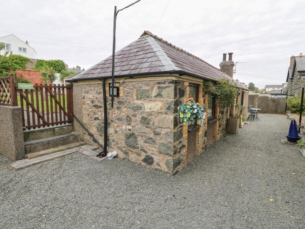 a small stone building with a roof at Fir Tree Cottage in Criccieth