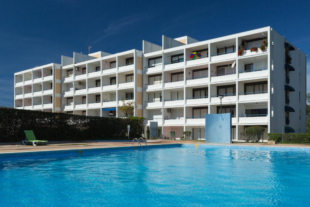 a hotel with a swimming pool in front of a building at Parque Mourabel, Oásis Village & Pé do Lago in Vilamoura