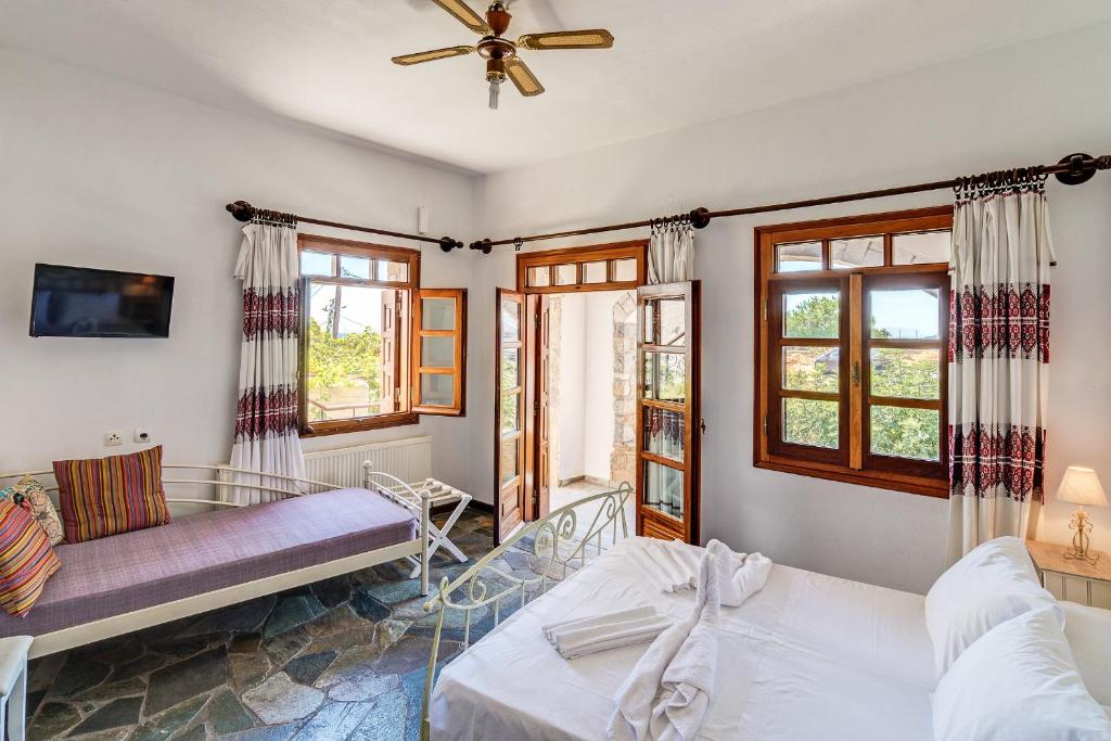 um quarto com uma cama, um sofá e janelas em Samaria Studios em Chora Sfakion